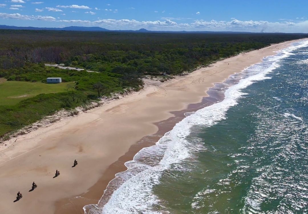 Expansive beach views, with a group of riders on the Noosa North Shorebeach