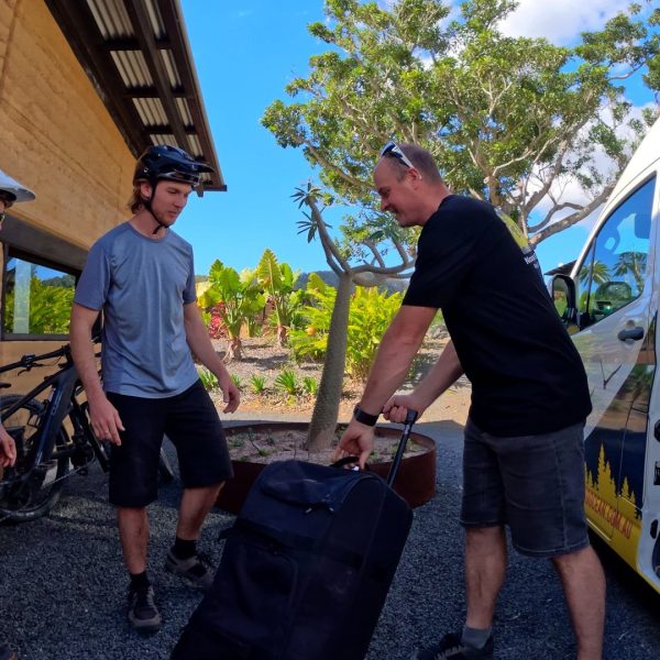 Guide handing over luggage from the support van on arrival, guided multi-day bike journey
