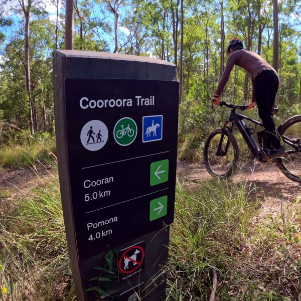 Rider passing the Cooroora Trail sign on the Noosa Trail Network