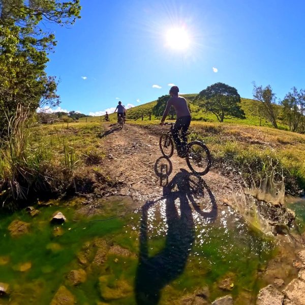 Rider through a creek crossing on a hillside trail, Noosa Hinterland