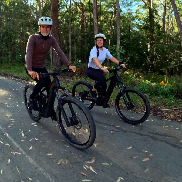 Two riders on electric mountain bikes on a forest road, Noosa Hinterland