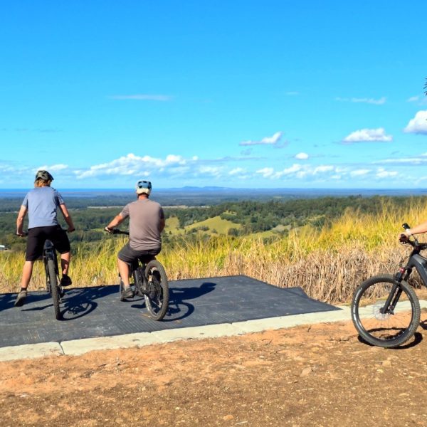 Riders on electric mountain bikes at a lookout over the Noosa Hinterland