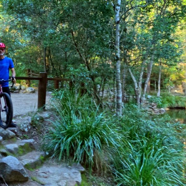 Two riders with their mountain bikes beside a rock pool, Noosa Hinterland